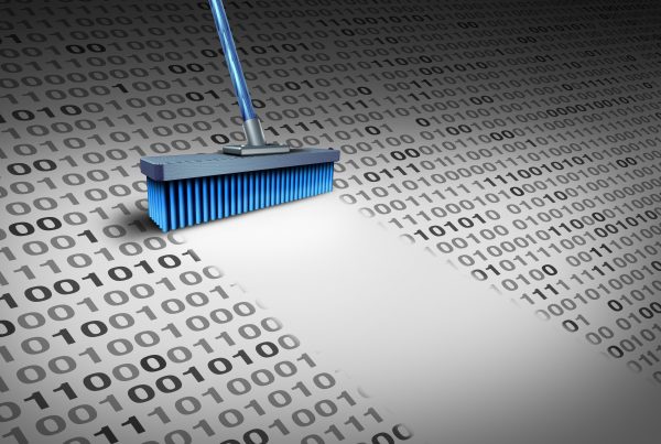 Uma imagem simbólica de uma vassoura limpando uma área cheia de números binários (0s e 1s), representando a importância da segurança cibernética e a ameaça dos ataques de phishing auxiliados por inteligência artificial.